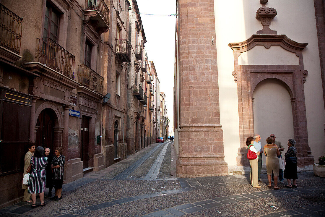 Menschen vor einer Kirche in der Altstadt im Abendlicht, Bosa, Sardinien, Italien, Europa