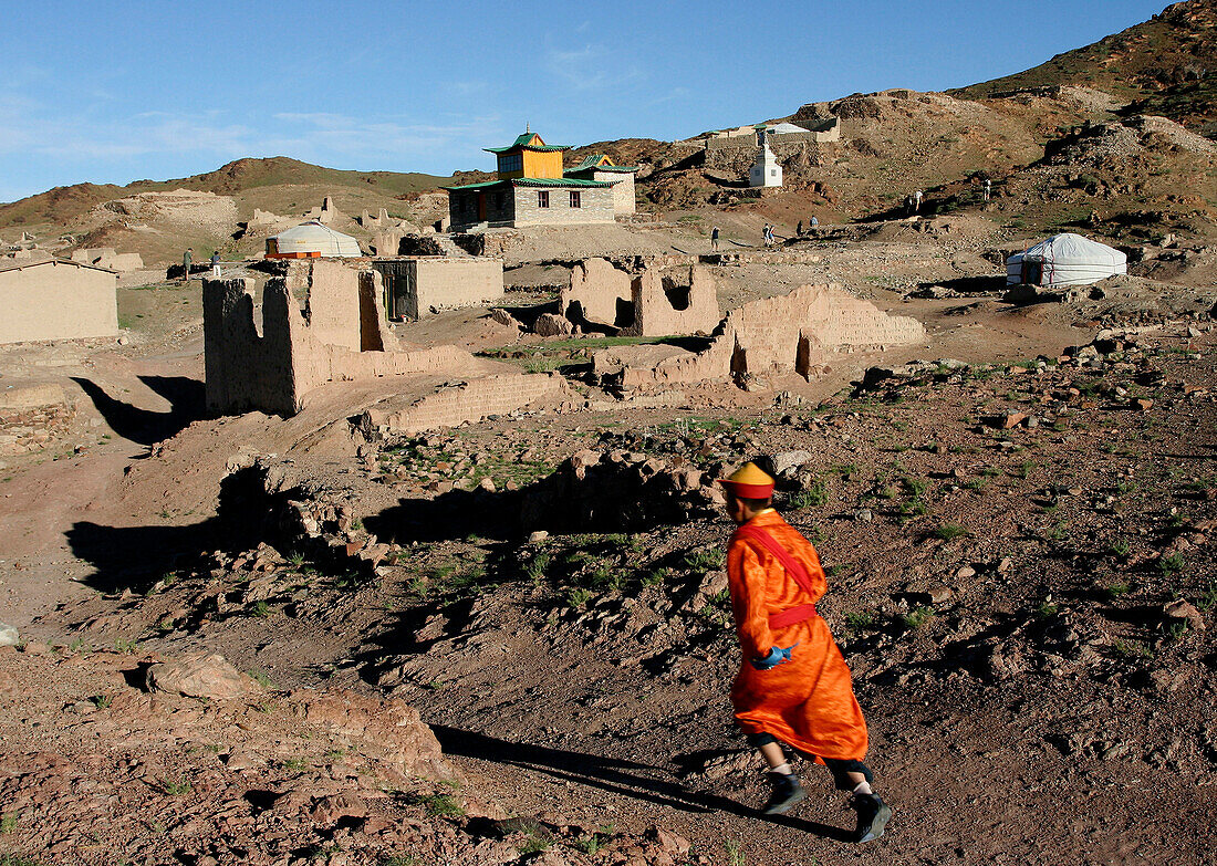 Temple and ruins in desert with running man in orange robes, General, Mongolia