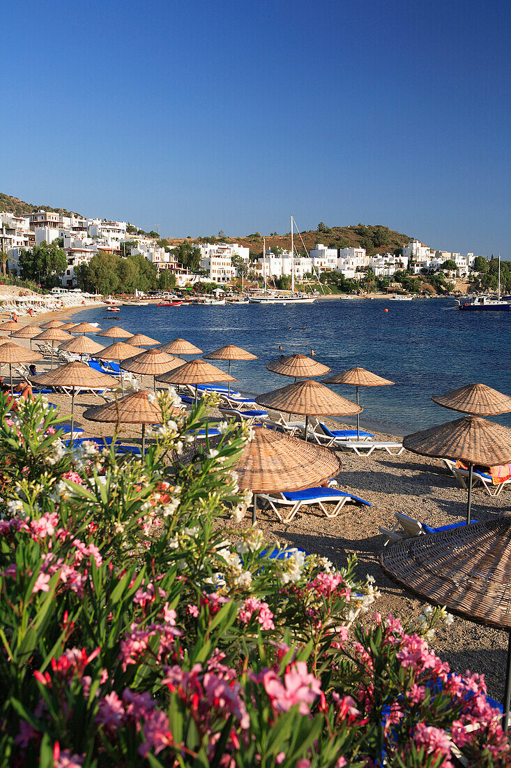 View over beach with sunshades to town and Outer Harbour, Bodrum, Aegean, Turkey