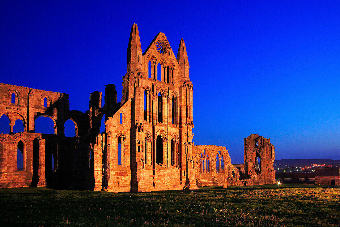 Whitby Abbey floodlit against blue sky at night, Whitby, Yorkshire, UK, England