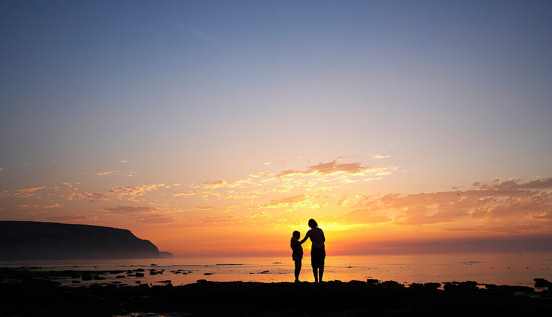 Ciffs at sunset from Cowbar with couple in silhouette, Boulby Cliffs, Yorkshire, UK, England