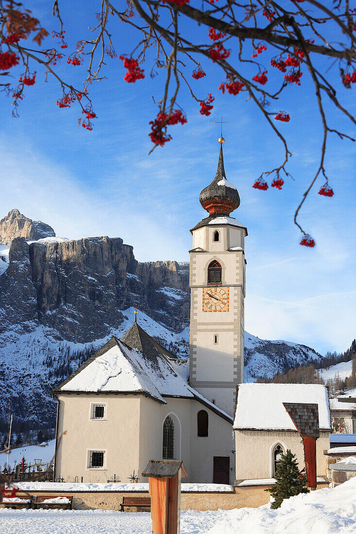 Church and Dolomites in winter framed by tree, Colfosco, Trentino-Alto Adige, Italy