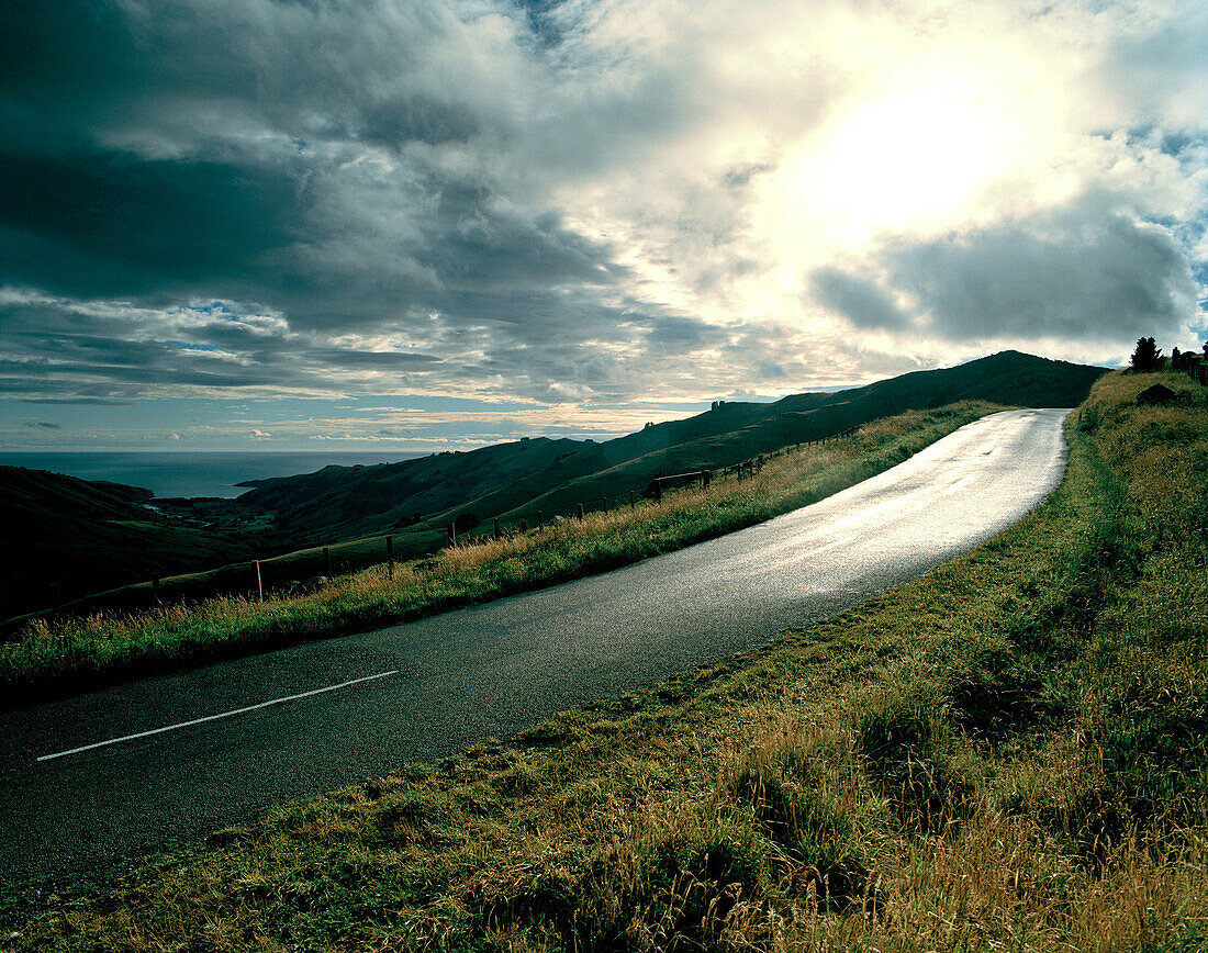 Summit Road and view over Okains Bay under grey clouds, Banks Peninsula, South Island, New Zealand