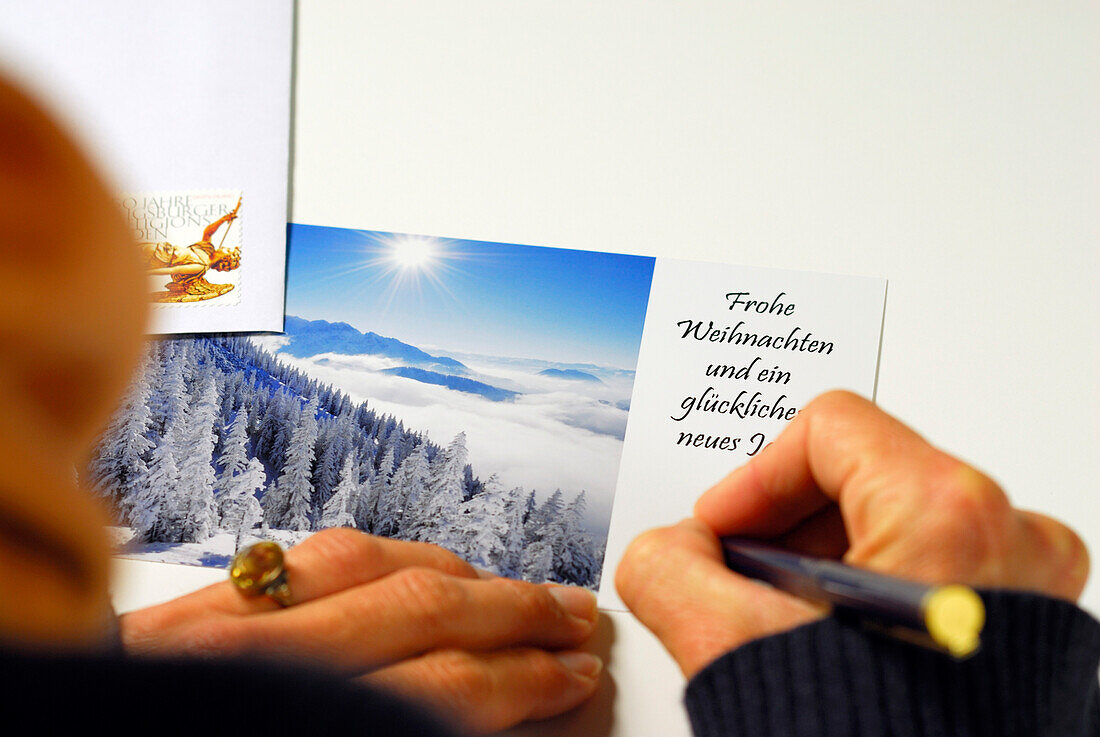 Frau schreibt Weihnachtskarte mit Wintermotiv