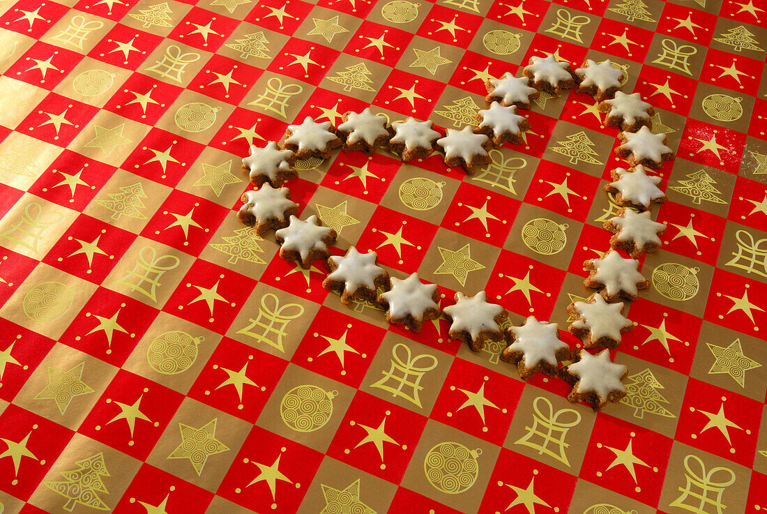 Christmas cookies cinnamon stars laying in heart shape on wrapping paper