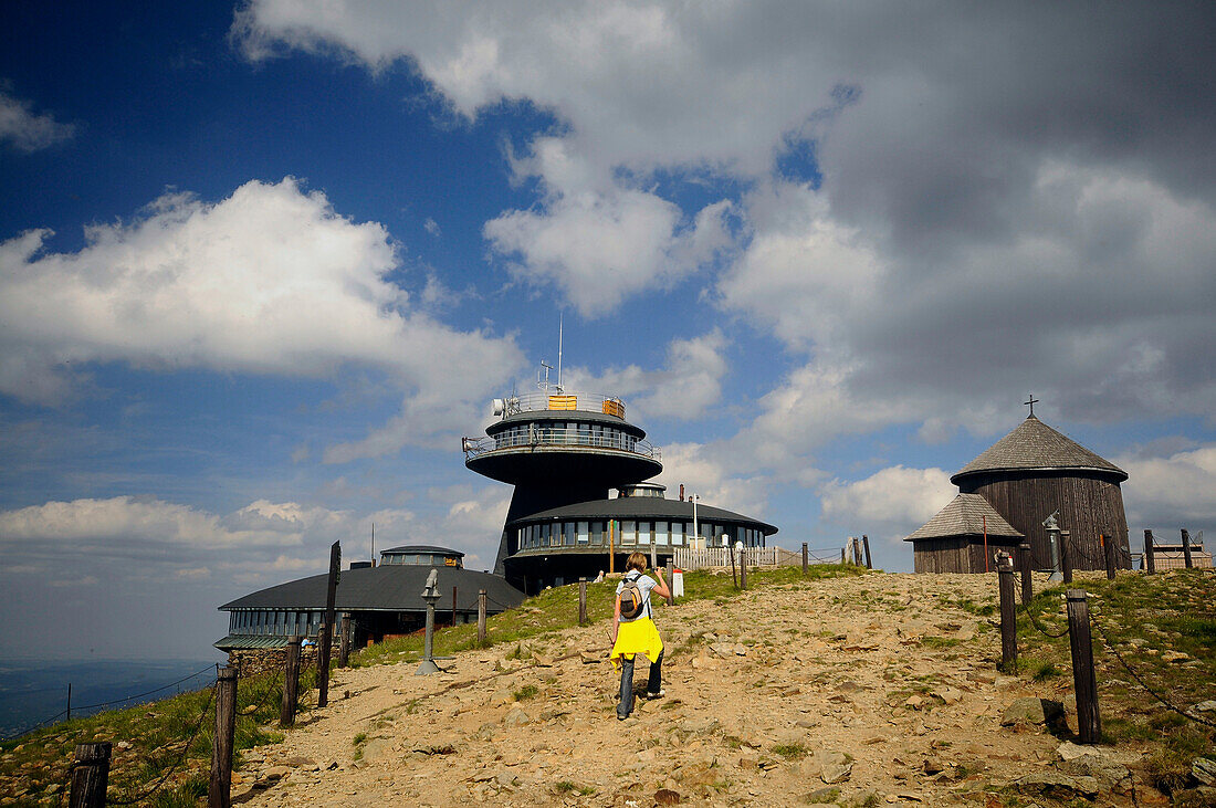 Hiker in front of buildings on the summit of the Schneekoppe, Bohemian mountains, Lower Silesia, Poland, Europe