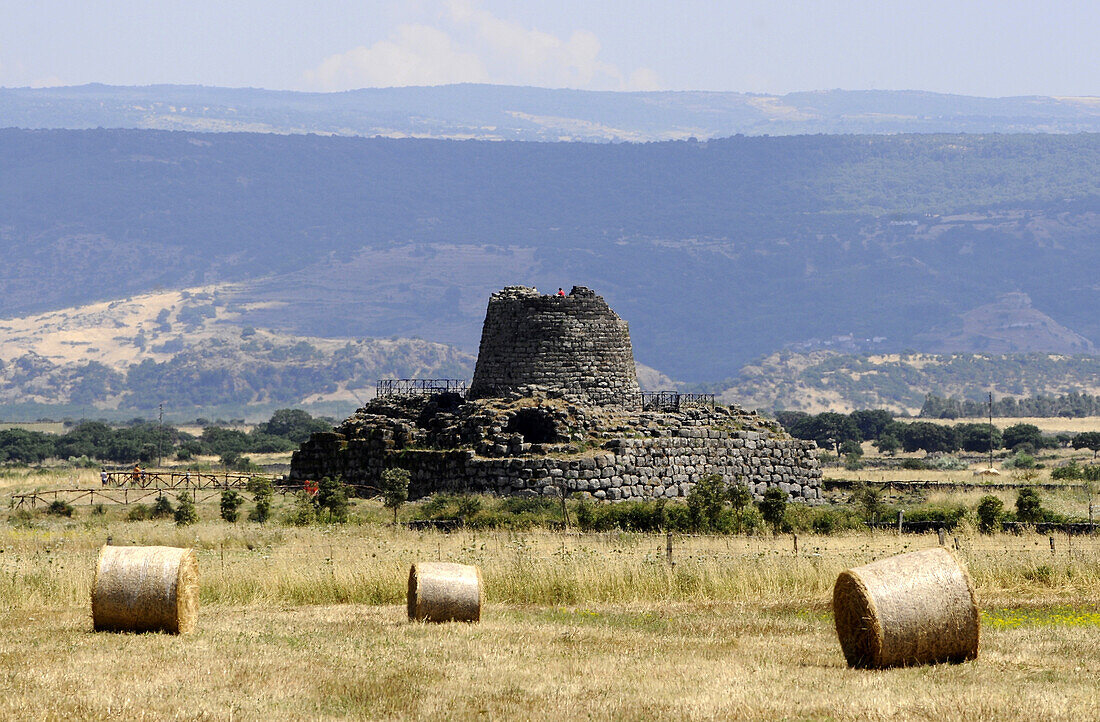 Field with hay bales in front of Nuraghe Santu Antine at Valle dei Nuraghi, Sadinia, Italy, Europe