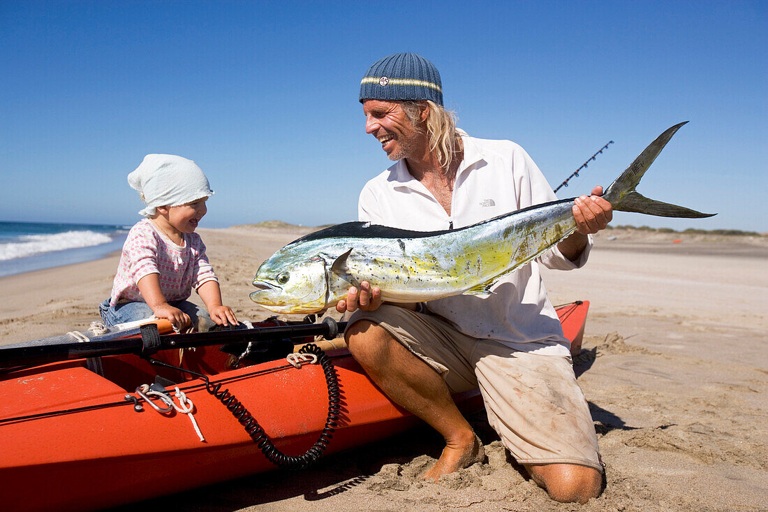 A man showing his little daughter his recently caught mahi-mahi, Punta Conejo, Baja California Sur, Mexico, America