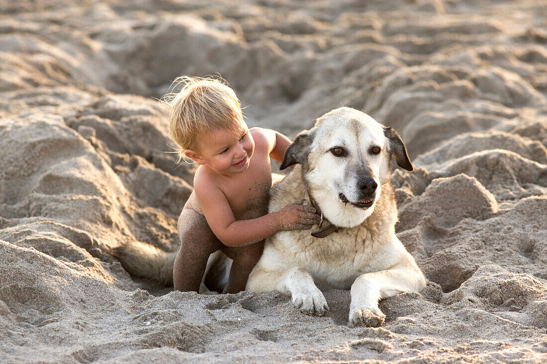 Kleines Mädchen spielt im Sand mit einem Hund, Punta Conejo, Baja California Sur, Mexiko, Amerika