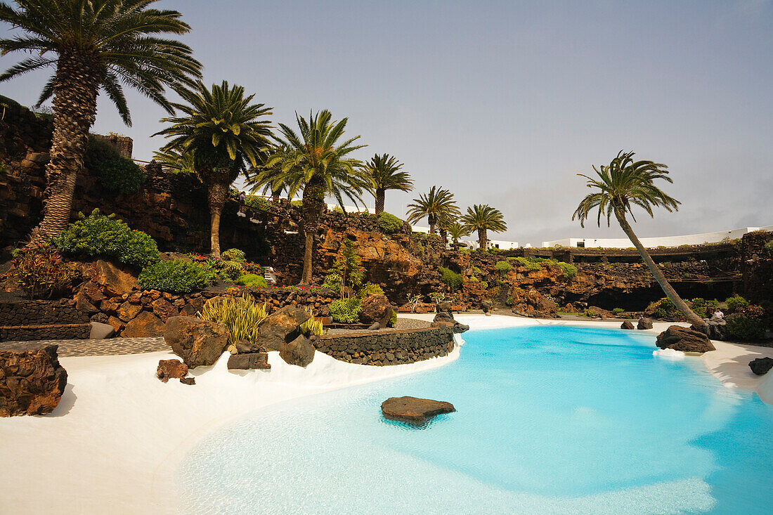 Swimming pool with palm trees near a volcanic cave, Jameos del Agua, hollow lava tunnel, architect Cesar Manrique, UNESCO Biosphere Reserve, Lanzarote, Canary Islands, Spain, Europe