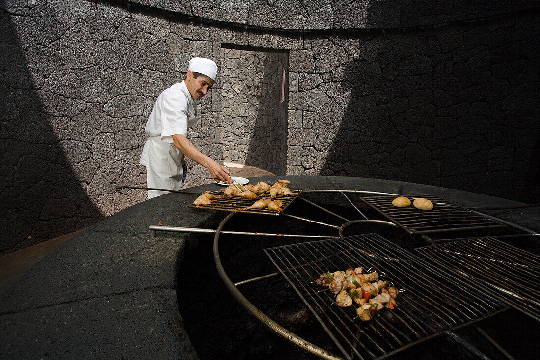 Cook cooking food on a volcanic grill, volcanic heat, Timanfaya Restaurant, architect Cesar Manrique, Parque Nacional de Tiimanfaya, Montanas del Fuego, Lanzarote, Canary Islands, Spain, Europe