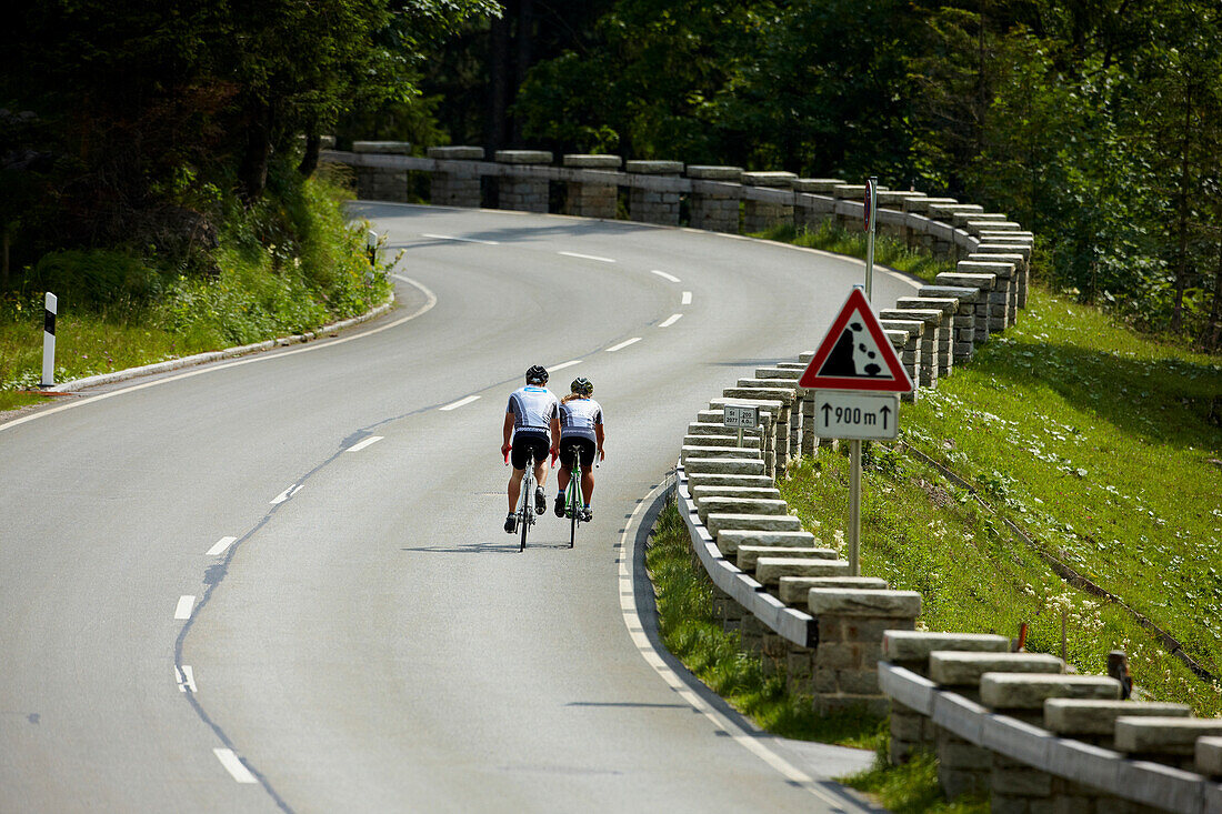 Two racing cyclists on bendy road, Spitzing, Bavaria, Germany