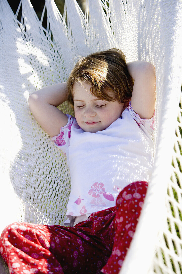 Little girl laying on a hammock in the garden