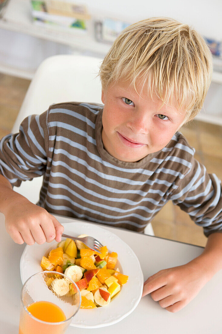 At home, Blond, Blonds, Blue eyed, Blue eyes, Blue-eyed, boy, boys, Caucasian, Caucasians, child, children, Color, Colour, Contemporary, Dish, Dishes, Eat, Eating, Facing camera, Fair-haired, Food, Foodstuff, Fork, Forks, From above, Fruit salad, healthy,