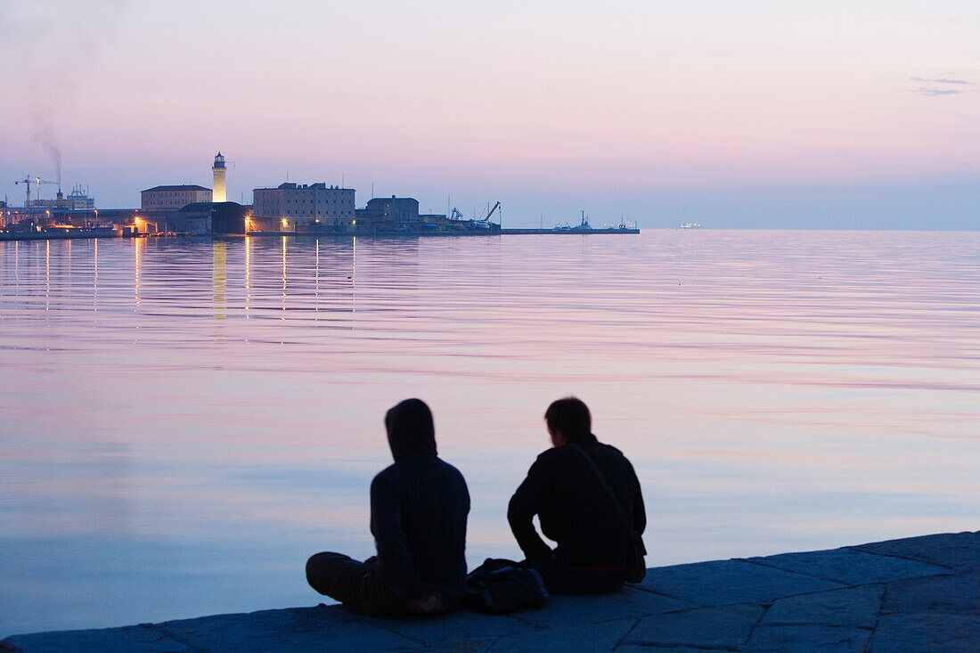 Two men sitting on Molo Audace, Molo Bersaglieri in the background, Trieste, Friuli-Venezia Giulia, Upper Italy, Italy