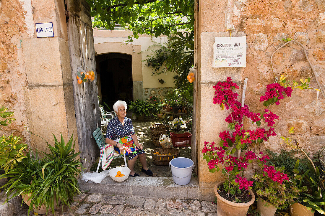 Alte Frau verkauft Orangen in einer Gasse, Fornalutx, Mallorca, Balearen, Spanien, Europa