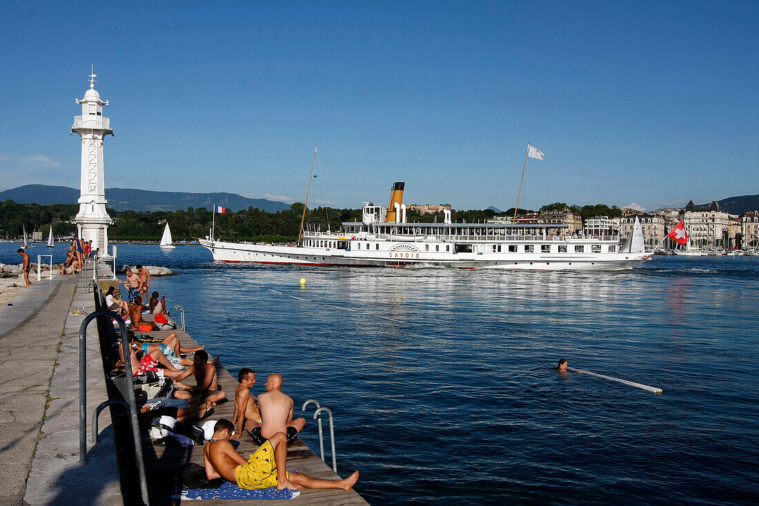 Bathing And Relaxing In Front Of The White Lighthouse Of The Bains Des Paquis In The Geneva Harbour On Lake Geneva, Geneva, Switzerland