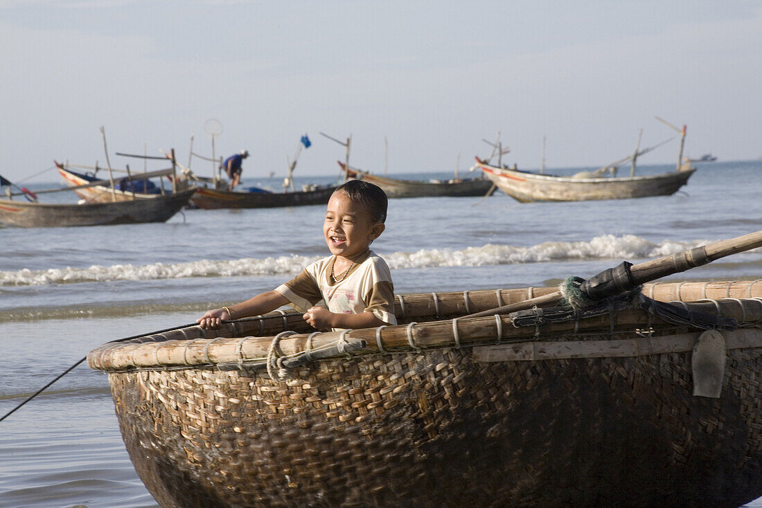 Vietnamesischer Junge in einem Fischerboot am Strand, Mui Ne, Provinz Binh Thuan, Vietnam, Asien