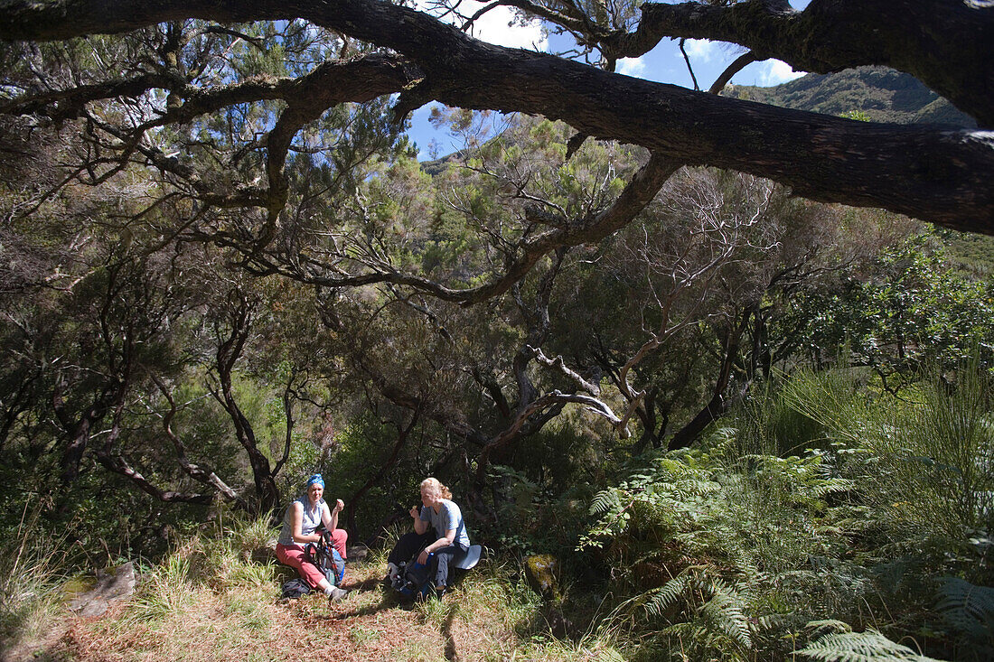 Two Women enjoying a rest on the Levada Walk to 25 Fontes waterfalls, Near Rabacaul, Madeira, Portugal