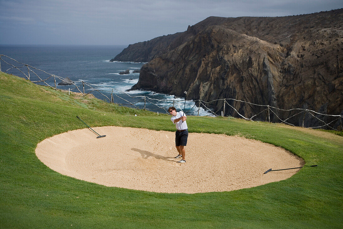 Golfer schlägt Ball aus Sandhindernis der Bahn 13 am Porto Santo Golfplatz, Porto Santo, nahe Madeira, Portugal