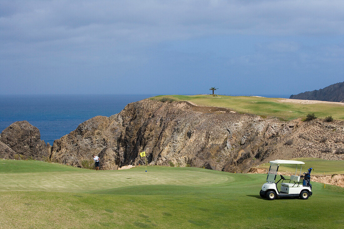 Golfer chipping ball from the green of Hole 15 at Porto Santo Golfe Golf Course, Porto Santo, near Madeira, Portugal