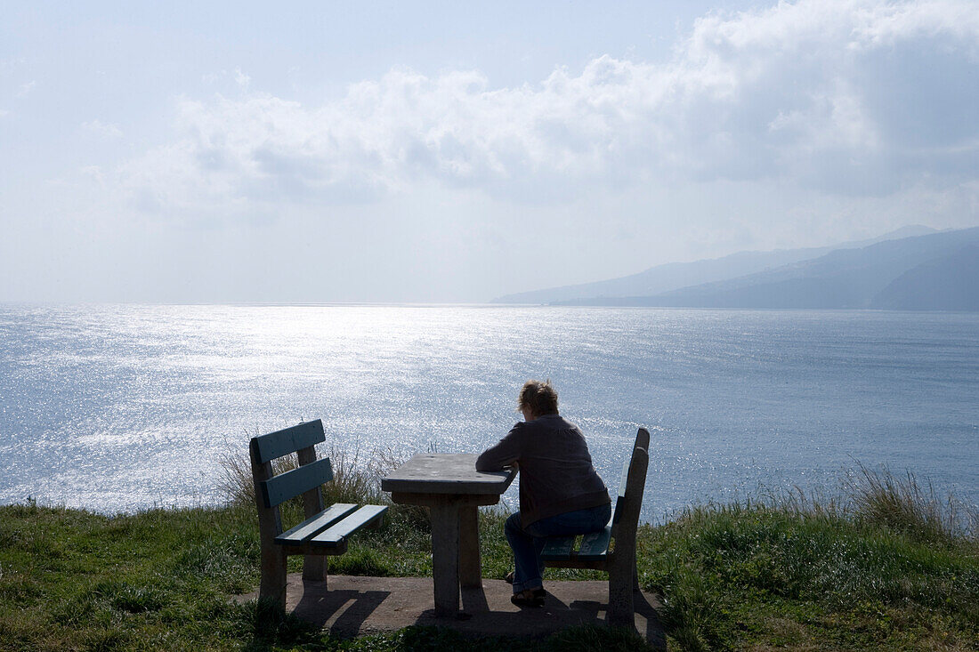 Woman sitting at a picnic table near Ponta de Sao Laurenco enjoying the view, Near Canical, Madeira, Portugal