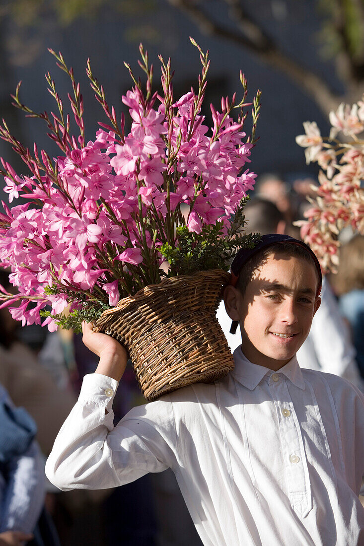 Junger Mann mit Korb voll Blumen bei der Parade zum alljährlich stattfindenden Madeira Blumenfest, Funchal, Madeira, Portugal