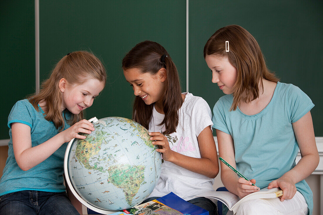 Schoolgirls with globe in classroom, Hamburg, Germany