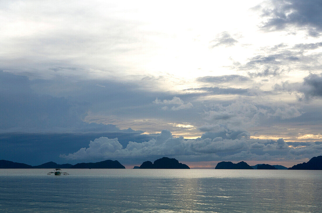 Fischerboot in der Corong-Corong Bay vor Kalksteininseln bei Sonnenuntergang, Bacuit-Archipel, El Nido, Palawan, Philippinen, Asien