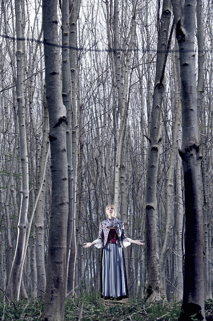 Young woman wearing a dirndl, traditional costume, standing in a forest, Kaufbeuren, Bavaria, Germany