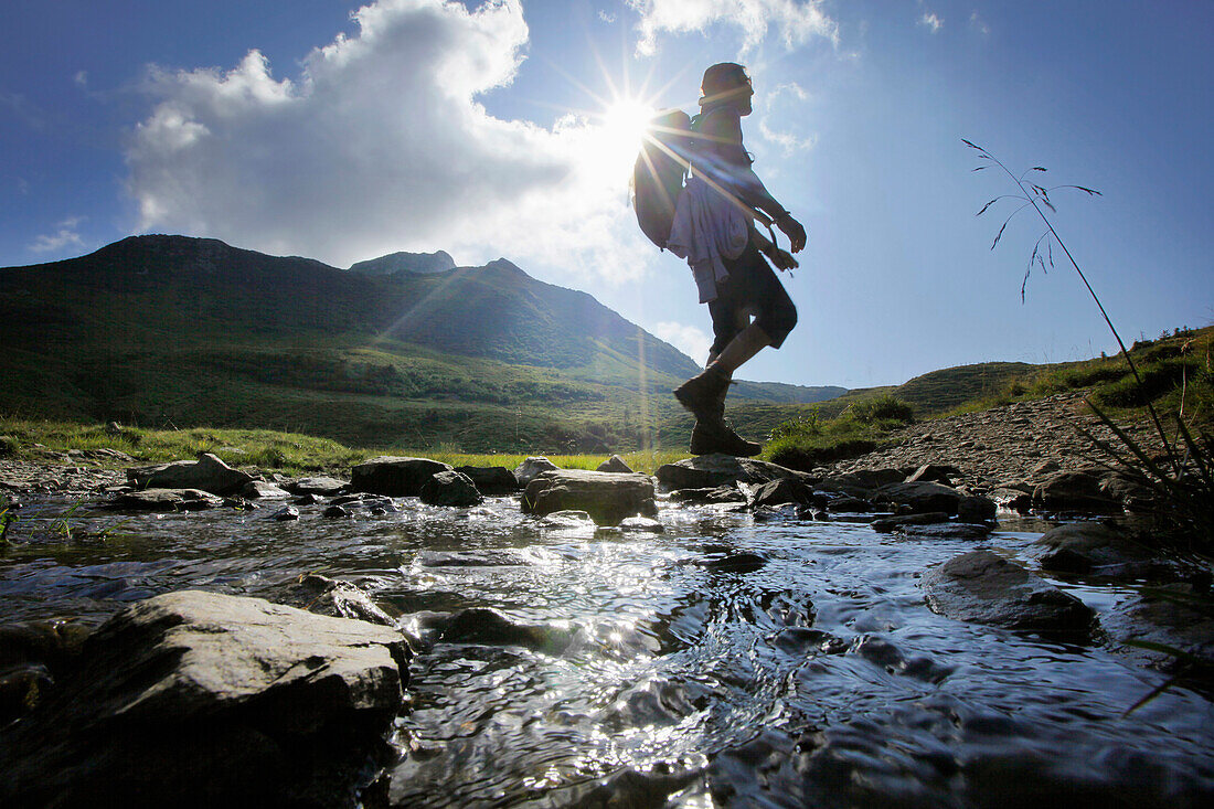 Female hiker passing stream, Carnic Alps, Carinthia, Austria