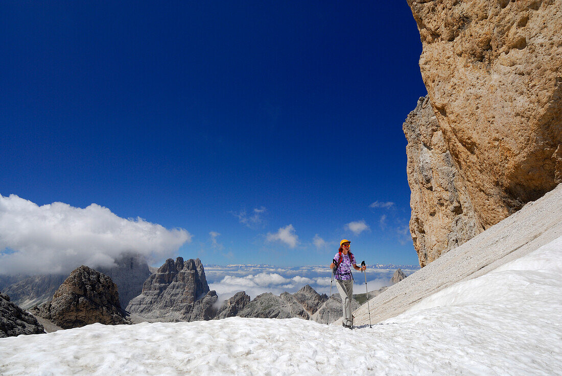 Frau wandert über Schnee am Antermoiapass mit Blick auf Vajolettürme, Rosengarten, Dolomiten, Südtirol, Italien