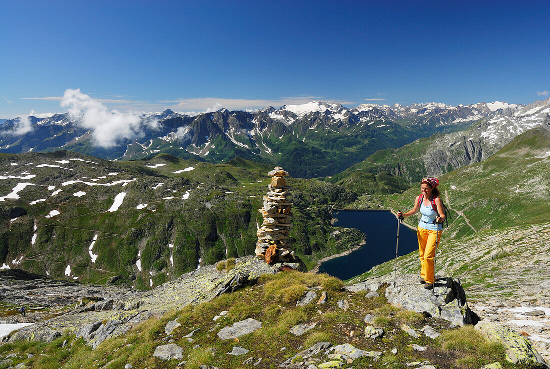 Woman near cairn above reservoir Lago della Sella, Gotthard range, Canton of Ticino, Switzerland