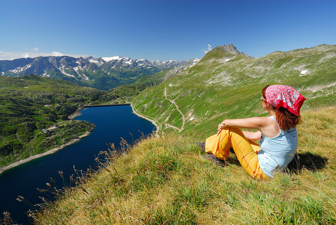 Woman looking over reservoir Lago della Sella  to Ticino Alps, Gotthard range, Canton of Ticino, Switzerland