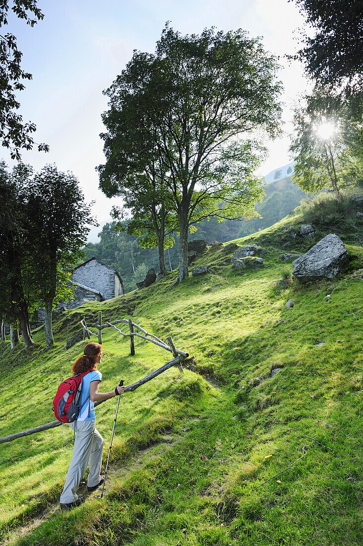 Woman mountain hiking, alpine hut in background, Monti Lariani, Lake Como, Lombardy, Italy