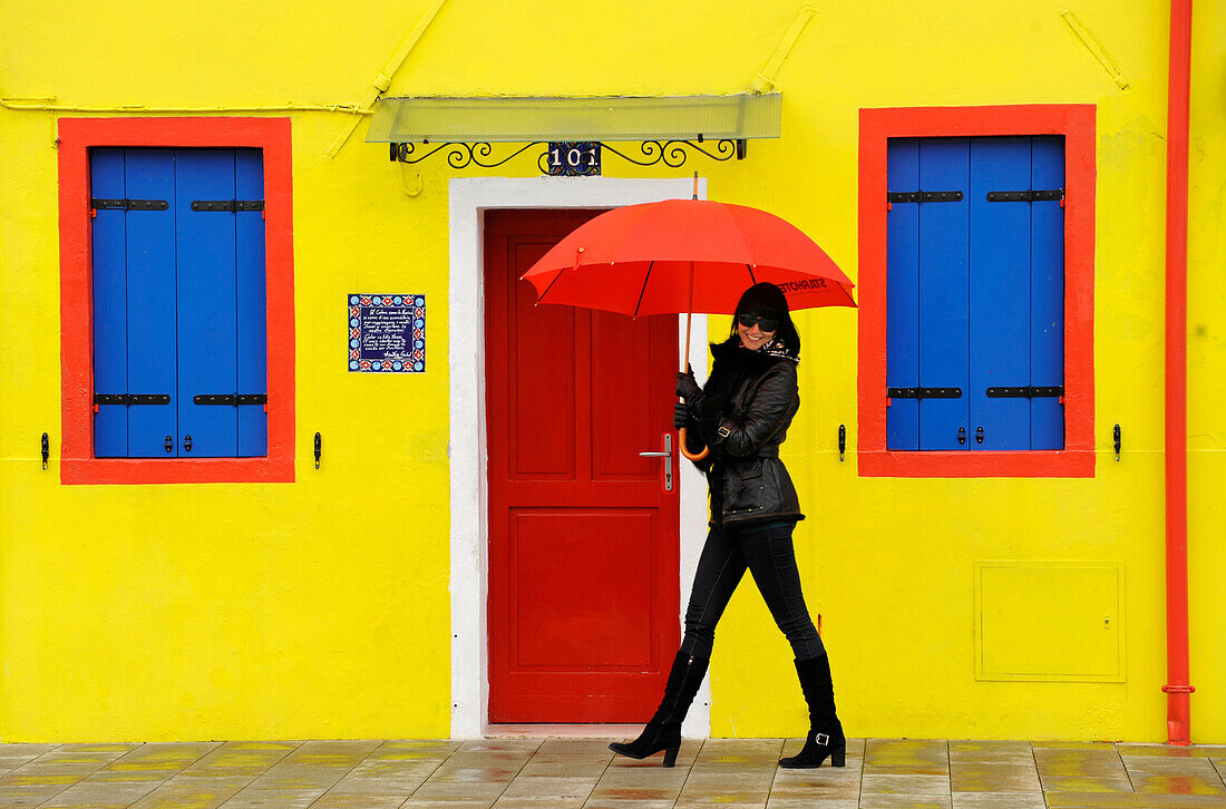 Frau mit Regenschirm läuft Strasse entlang, Burano, Venedig, Veneto, Italien