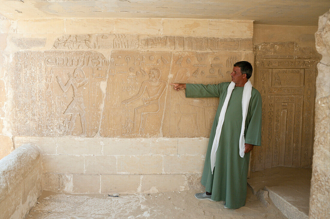 Guide shows Inscription at Mastaba near Saqqara Step Pyramid of Pharaoh Djoser, Egypt, Saqqara