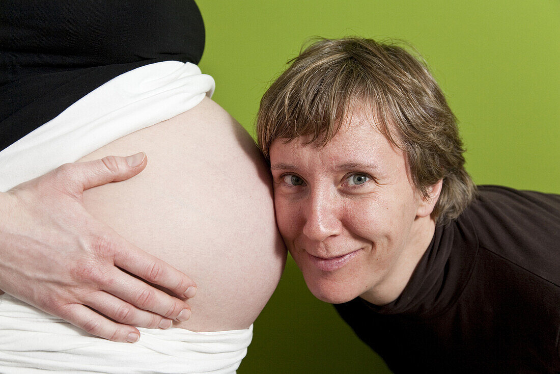 Frau horcht am Bauch einer Schwangeren, Bad Oeynhausen, Nordrhein-Westfalen, Deutschland