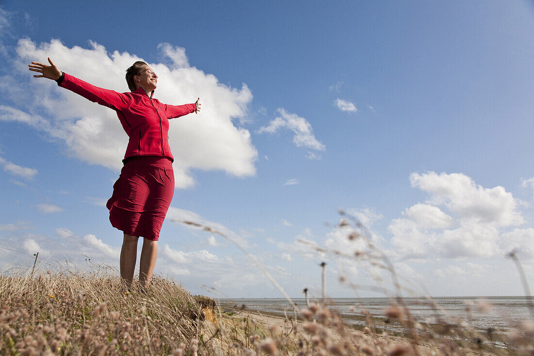 Woman with outstreched arms at beach of Utersum, Foehr island, Schleswig-Holstein, Germany
