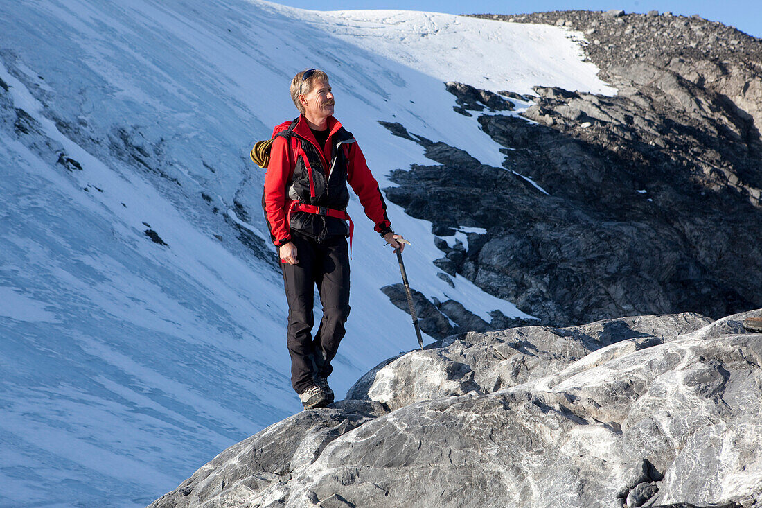 Bergsteiger mit Eispickel steht auf einem Felsen, Clariden, Kanton Uri, Schweiz