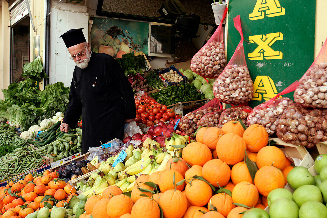 Orthodox Priest In Front Of A Fruit And Vegetables Stall, Crete, Greece