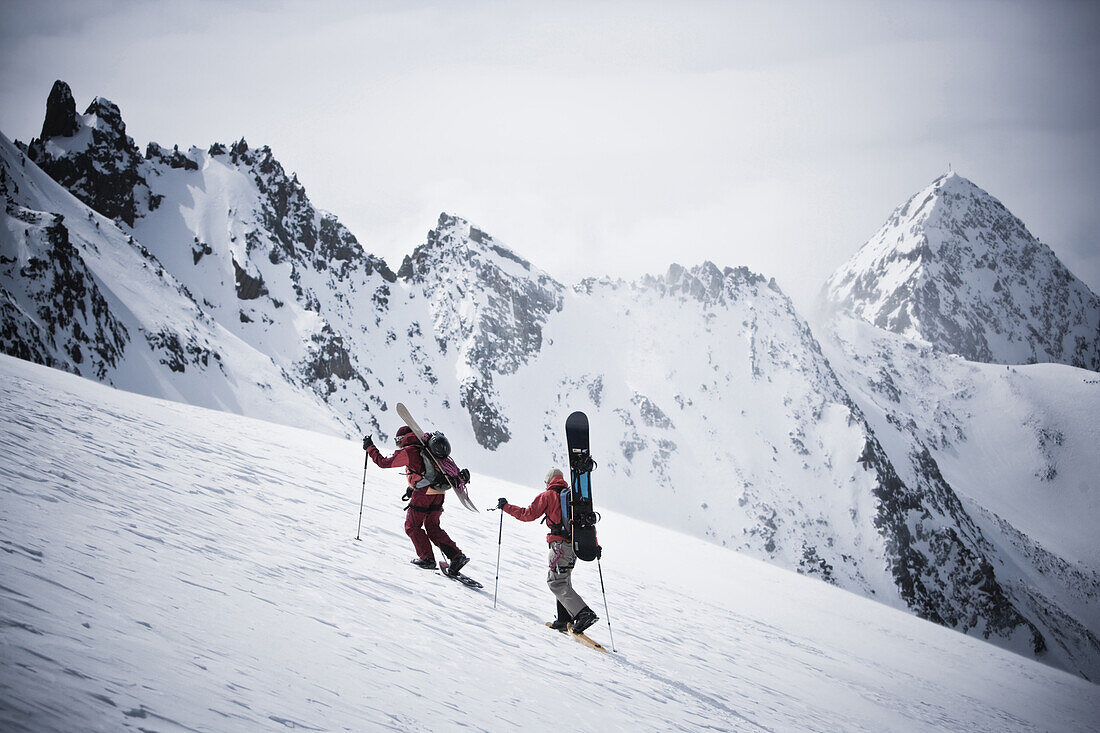 Two snowboarders ascending Zuckerhuetl, Gaiskogl in background, Stubai Alps, Tyrol, Austria
