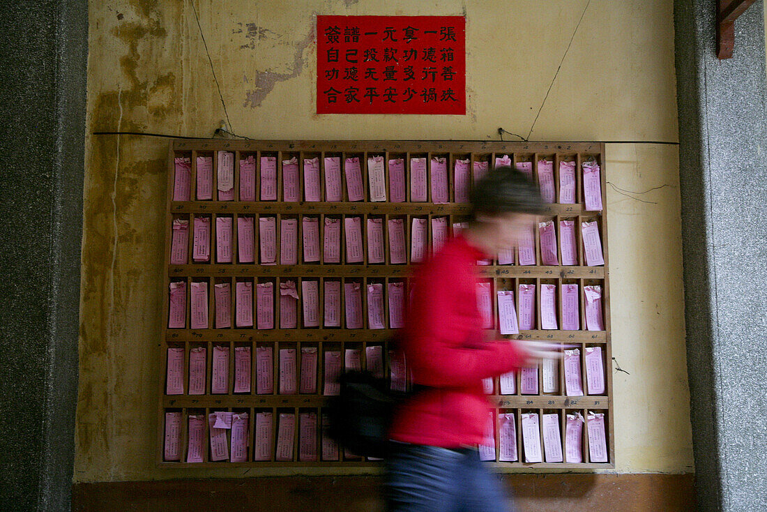 Buddhistischer Tempel in einer Kleinstadt, europäische Frau vor einem Regal mit rosa Zetteln, beschrieben mit religiösen Sprüchen, Jinfeng, Changle, Fujian, China, Asien