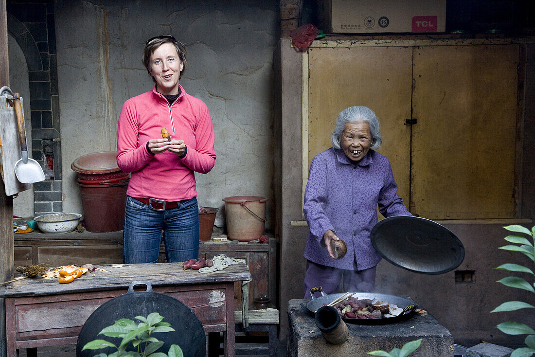 Old chinese woman and german tourist at the courtyard of a roundhouse of the Hakka, Hongkeng, Longyan, Fujian, China, Asia