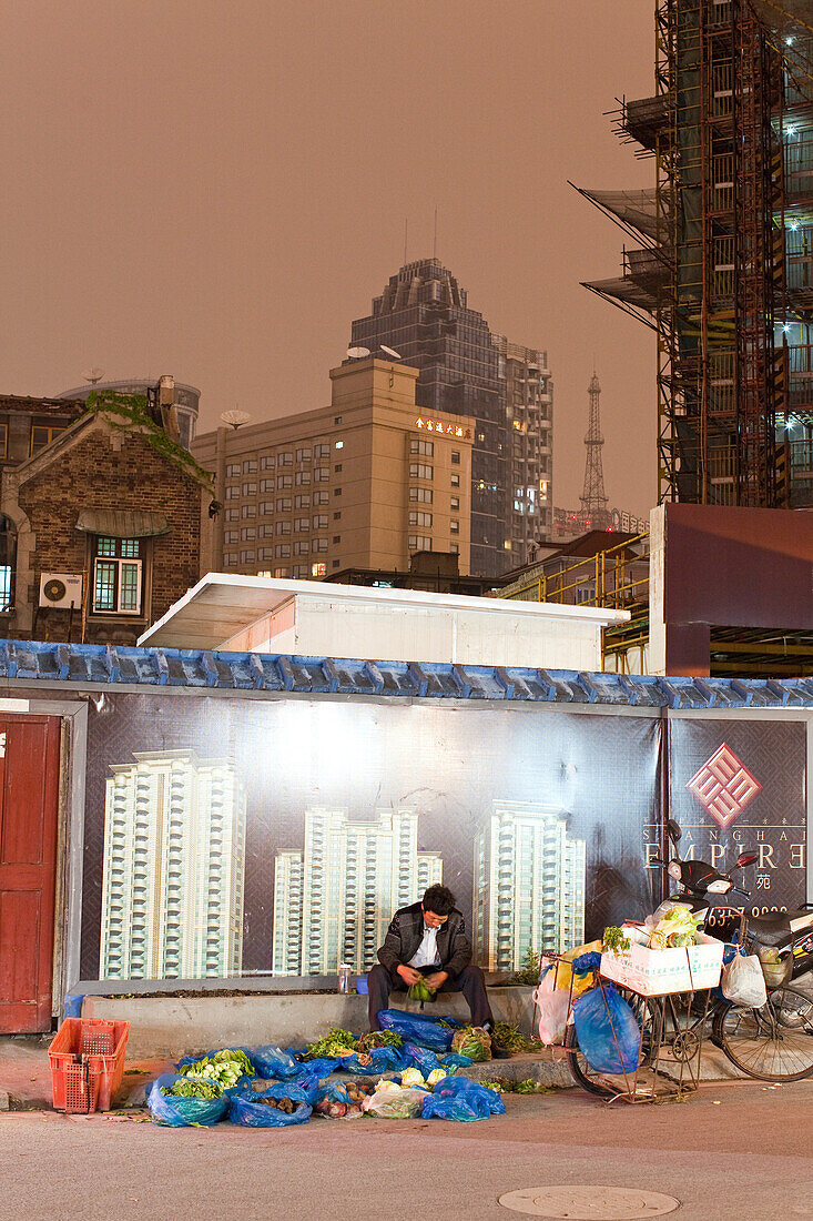Gemüsehändler mit Fahrrad vor beleuchtetem Werbeplakat am Abend, Hongkou, Shanghai, China, Asien
