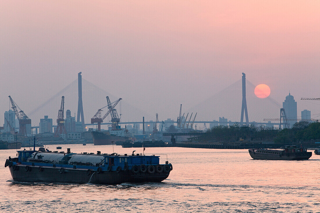 Schiffe auf dem Fluss Huangpu und Kräne am Hafen bei Sonnenuntergang, Pudong, Shanghai, China, Asien