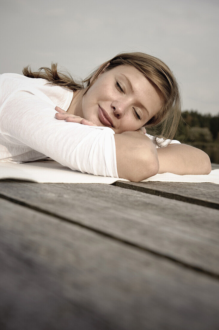 Junge Frau liegt auf einem Steg, Starnberger See, Bayern, Deutschland
