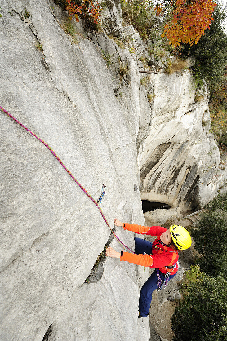 Frau klettert an einer Felswand, Torbole-Nago, Gardasee, Trentino-Südtirol, Italien