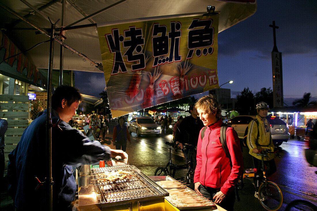 Tourist kauft gegrillten Tintenfisch auf Nachtmarkt, Kenting Nationalpark, Kending, Kenting, Republik China, Taiwan, Asien