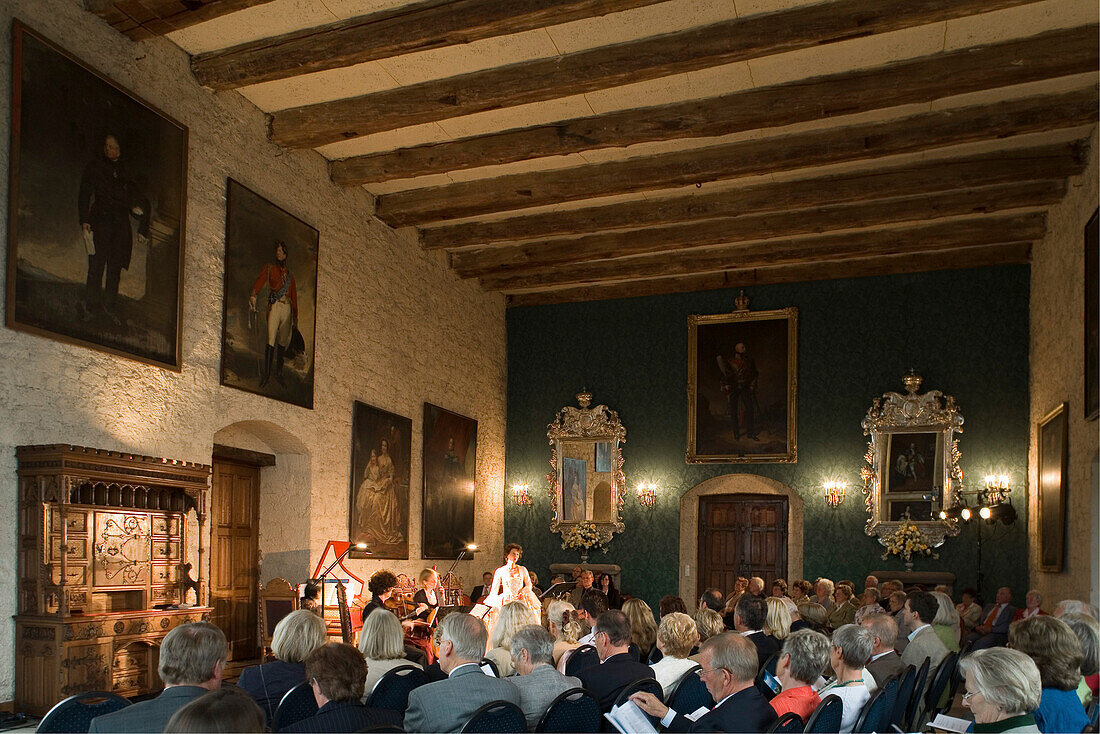 Konzert im Schloss saal der Marienburg, Publikum, Konzertflügel, Klavierspieler, Sängerin, Cellistin, Holzbalken, Gemälde